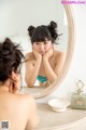 A woman looking at her face in the mirror.