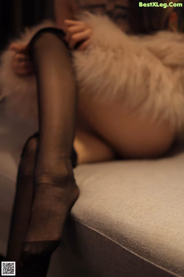 A woman in black stockings is laying on a couch.