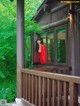 A woman in a red dress standing on a porch.