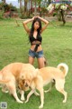 A woman standing next to two dogs in a grassy field.