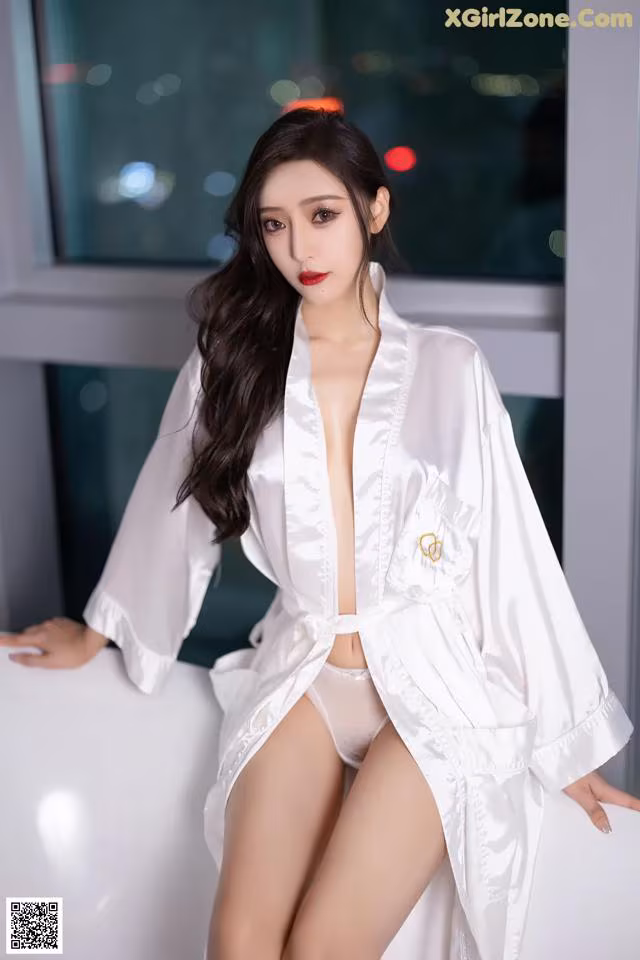 A woman in a white robe sitting on a white couch.