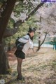 A woman in a school uniform standing next to a tree.