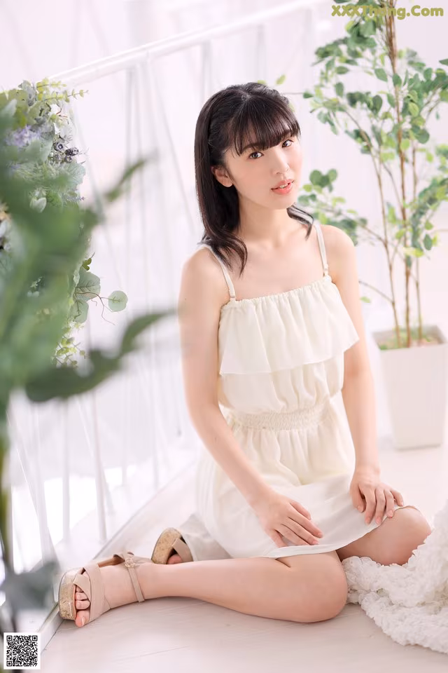 A woman in a white dress sitting on the floor.