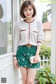 a woman standing in front of a window wearing a green skirt