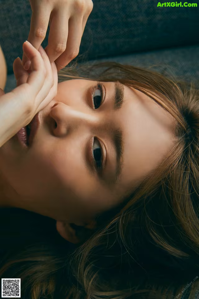 A woman laying on a couch with her hand on her face.