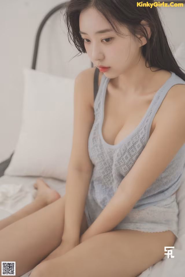 a woman sitting on top of a bed next to a pillow