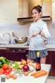 A woman in a kitchen preparing food on a counter.