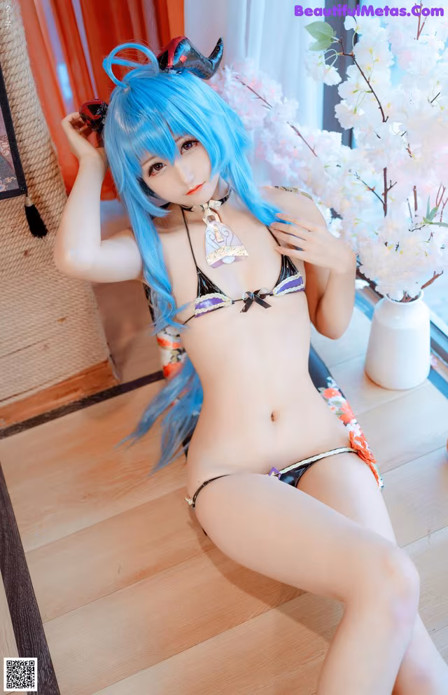A woman in a bikini sitting on a wooden floor.