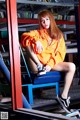 A woman sitting on top of a blue chair in a library.