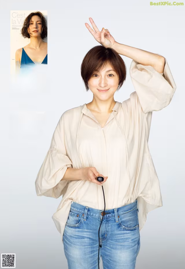 A woman in a white shirt and blue jeans posing for a magazine.
