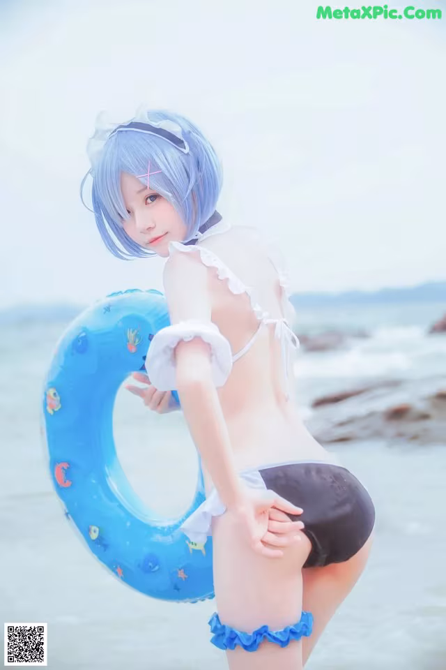 A woman in a bikini holding an inflatable ring on the beach.
