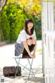 A woman in a school uniform sitting on a chair.