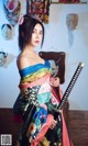 A woman in a kimono holding a samurai sword.