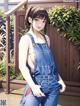 A woman in overalls is posing for the camera.