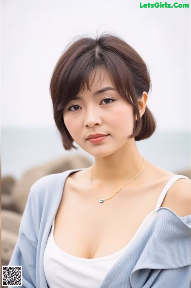 A woman wearing a blue cardigan and a white top.