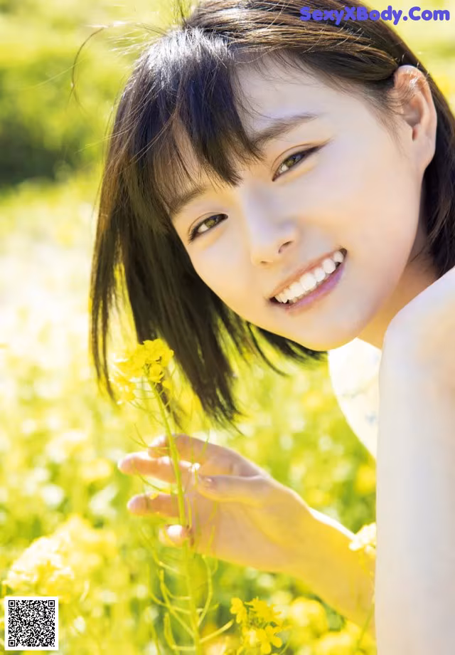 A young woman in a field of yellow flowers.