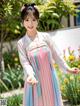 A woman in a pink and blue hanbok standing in a garden.