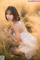 A woman in a white dress sitting in tall grass.