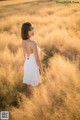 A woman in a white dress standing in a field.