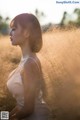 A woman in a white dress sitting in a field of tall grass.