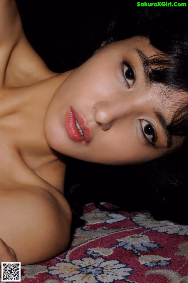 A woman laying on top of a rug next to a pillow.