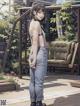 A woman in overalls standing on a wooden deck.