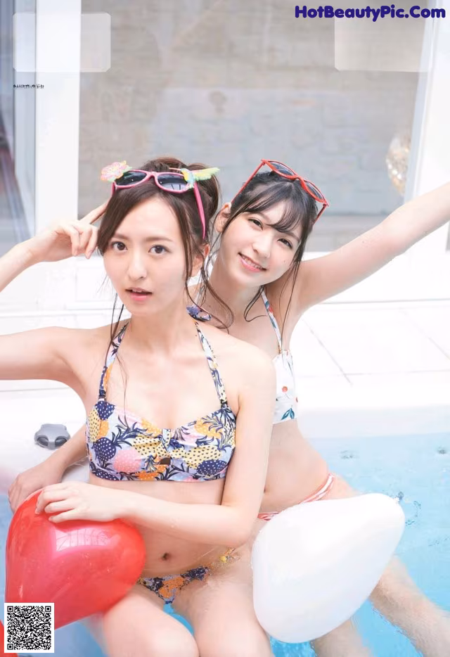 A couple of women sitting next to each other in a pool.